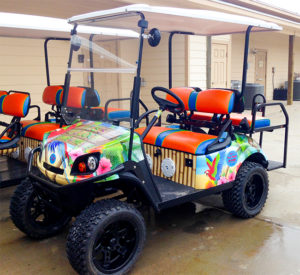 It's 5 O'Clock Somewhere Golf cart with bright flowers and parrots.